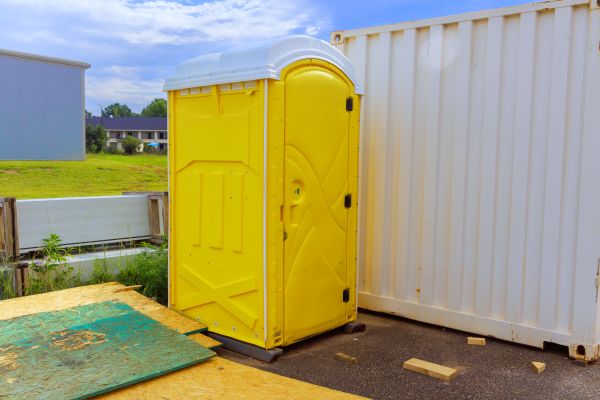 Jobsite porta potty rental beside construction equipment in Portland and the Pacific Northwest